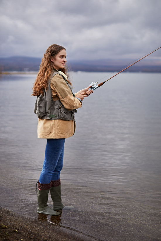 An image of a lady out fishing in a shallow area of a lake wearing Pokeboo Packable Waterproof Boots in a Khaki colour
