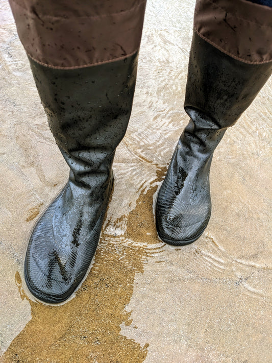 Walking on a beach and in water from the sea wearing Black Pokeboo Packable Boots